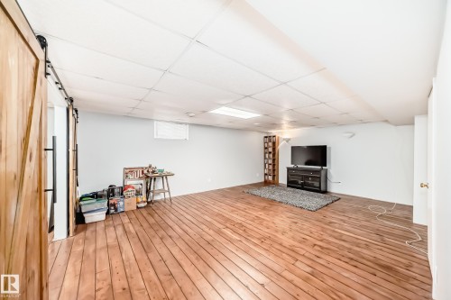 Spacious room featuring hardwood flooring and a ceiling with recessed lighting - 4446 116 Avenue, Edmonton, AB 