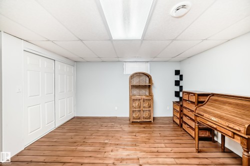 Spacious room featuring hardwood flooring, white walls, and a recessed ceiling with overhead lighting - 4446 116 Avenue, Edmonton, AB 