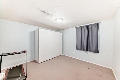 This room features carpeted flooring, light-colored walls, and a window with curtains - 4446 116 Avenue, Edmonton, AB 