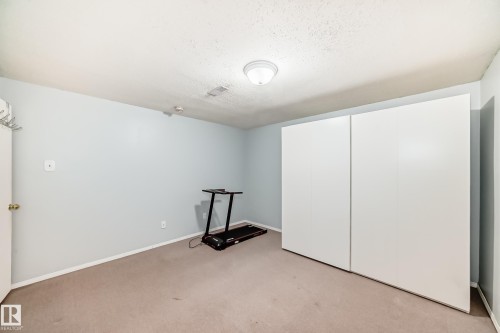 This room features light-colored carpeting, pale blue walls, and a ceiling light fixture - 4446 116 Avenue, Edmonton, AB 