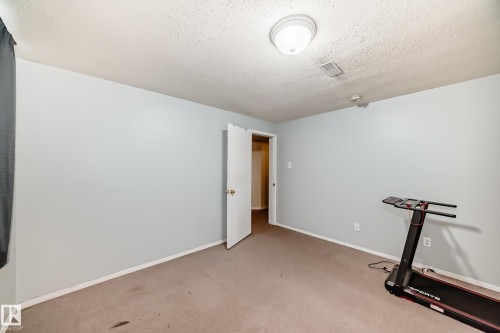 This room features light blue walls, a neutral carpet, and a white ceiling with a flush-mount light fixture - 4446 116 Avenue, Edmonton, AB 
