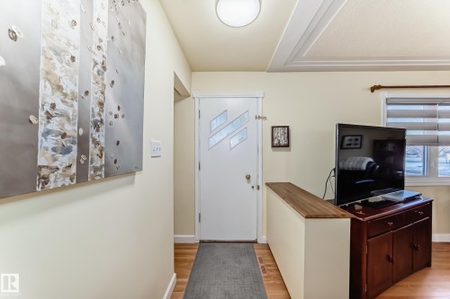 The entryway features light-colored walls and hardwood flooring, leading to a front door with decorative glass inserts - 4446 116 Avenue, Edmonton, AB 