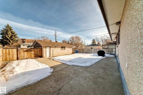 The property features a detached garage and a wooden fence, with a paved area and a patch of grass - 4446 116 Avenue, Edmonton, AB 