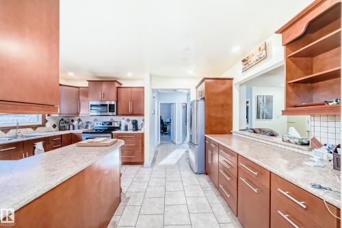 Spacious kitchen featuring extensive cabinetry, light-colored countertops, stainless steel appliances, and tiled flooring - 4446 116 Avenue, Edmonton, AB 