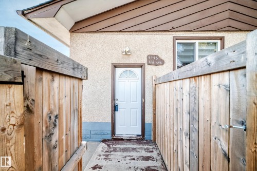The property features a white front door with an arched window, textured exterior walls, and a window with brown trim - 4446 116 Avenue, Edmonton, AB 