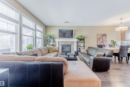 Living area featuring large windows letting in loads of natural light, a fireplace with mantel & tile surround & hardwood flooring. - 1312 74 Street, Edmonton, AB - Indoor Photo Showing Living Room With Fireplace