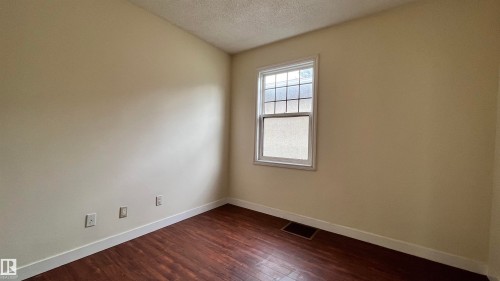 This room features wood flooring, light-colored walls, and a window with white trim - 10839 109 Street, Edmonton, AB - Indoor Photo Showing Other Room