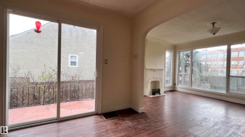 Spacious interior featuring hardwood floors, large windows providing natural light, and a decorative fireplace - 10839 109 Street, Edmonton, AB - Indoor Photo Showing Other Room