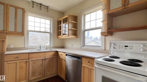 The kitchen features wood cabinetry, a double basin sink, and a white electric range - 10839 109 Street, Edmonton, AB - Indoor Photo Showing Kitchen With Double Sink