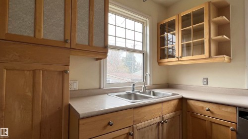 The kitchen features light wood cabinetry, a double basin stainless steel sink, and light-colored countertops - 10839 109 Street, Edmonton, AB - Indoor Photo Showing Kitchen With Double Sink