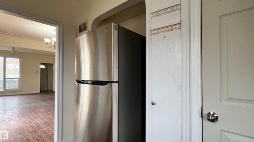 Kitchen area featuring a stainless steel refrigerator and an interior door with a silver handle - 10839 109 Street, Edmonton, AB - Indoor