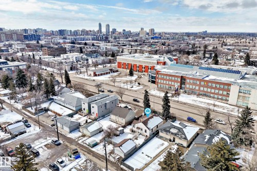 Aerial view showcasing the property within a neighborhood featuring residential buildings, a multi-story institutional building with solar panels, and a city skyline in the distance - 10839 109 Street, Edmonton, AB - Outdoor With View