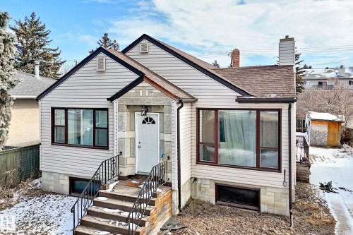 Property exterior featuring light-colored siding, a dark roof, and a front entryway with a white door - 10839 109 Street, Edmonton, AB - Outdoor