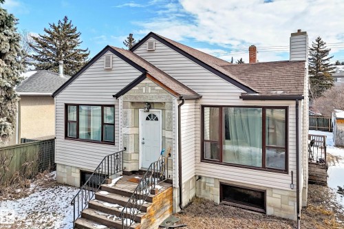 The property features light-colored siding, a dark-pitched roof, and a white front door with a decorative window - 10839 109 Street, Edmonton, AB - Outdoor
