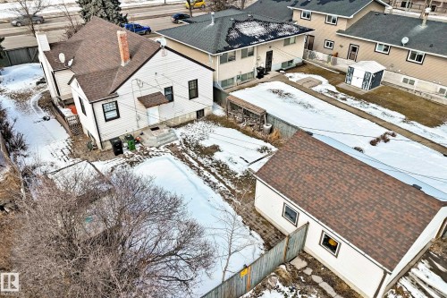 This property features a single-story detached home with white siding and a brown shingled roof, a chimney, and a detached garage with a matching brown shingled roof - 10839 109 Street, Edmonton, AB - Outdoor