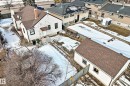 This property features a single-story detached home with white siding and a brown shingled roof, a chimney, and a detached garage with a matching brown shingled roof - 10839 109 Street, Edmonton, AB  - Outdoor 