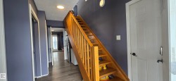 Hallway featuring a wooden staircase, recessed lighting, and dark grey walls - 
