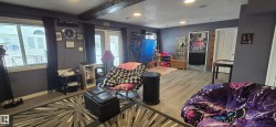 This spacious room features light wood-style flooring, a large window, and double doors providing exterior access - 