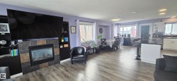 Living area featuring a fireplace with stone tile surround, built-in shelving, and light-toned flooring - 