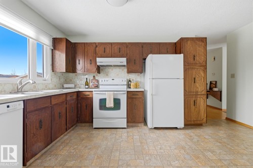 The property features a kitchen with wood cabinetry, a white refrigerator, and a white oven - 16108 100 Street, Edmonton, AB - Indoor Photo Showing Kitchen