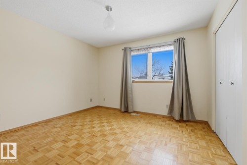 This room features parquet flooring, a window providing natural light, and a closet with bifold doors - 16108 100 Street, Edmonton, AB - Indoor Photo Showing Other Room