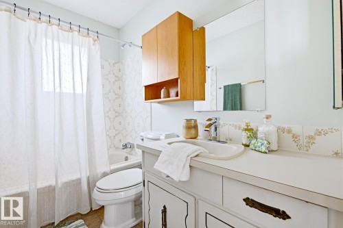 The bathroom features a bathtub with a shower, a toilet, and a vanity with an integrated sink - 16108 100 Street, Edmonton, AB - Indoor Photo Showing Bathroom