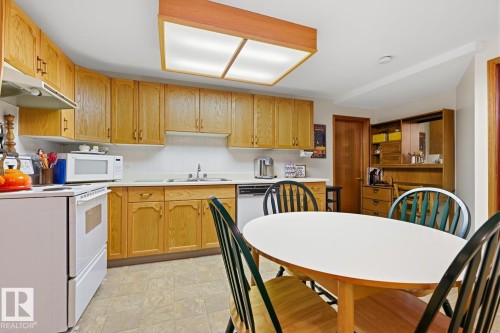 The kitchen features light wood cabinetry, white countertops, and a white tile backsplash - 16108 100 Street, Edmonton, AB - Indoor Photo Showing Kitchen With Double Sink