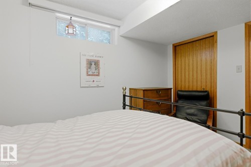 This room features a window providing natural light, a wooden door, and light-colored walls - 16108 100 Street, Edmonton, AB - Indoor Photo Showing Bedroom