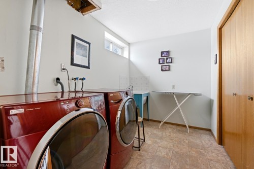 The laundry room features two front-loading machines, a utility sink, a window, and a wooden closet door - 16108 100 Street, Edmonton, AB - Indoor Photo Showing Laundry Room