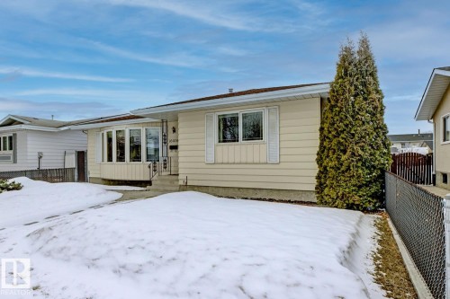 The property features light-colored siding, a front bay window, and a pathway leading to the entrance - 16108 100 Street, Edmonton, AB - Outdoor