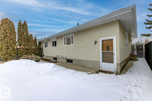 The property features a stucco exterior with multiple windows and a side entry door - 16108 100 Street, Edmonton, AB - Outdoor With Exterior