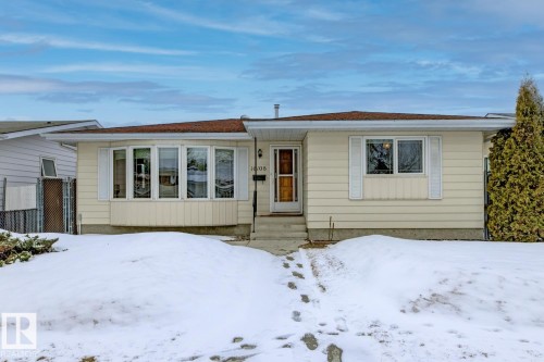 The property features a charming exterior with light-colored siding, a brown shingle roof, and a prominent bay window - 16108 100 Street, Edmonton, AB - Outdoor