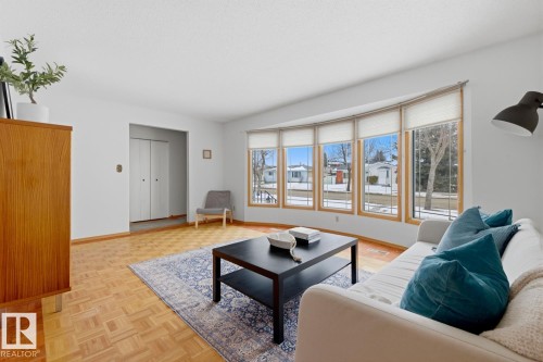 Spacious living area featuring light-toned parquet flooring and a large bay window with natural wood trim - 16108 100 Street, Edmonton, AB - Indoor Photo Showing Living Room
