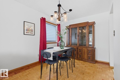 This dining area features parquet wood flooring and a window with horizontal blinds and red curtains - 16108 100 Street, Edmonton, AB - Indoor Photo Showing Dining Room