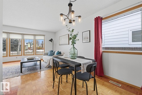 Living area featuring parquet wood flooring, large windows, and a ceiling-mounted chandelier - 16108 100 Street, Edmonton, AB - Indoor Photo Showing Dining Room