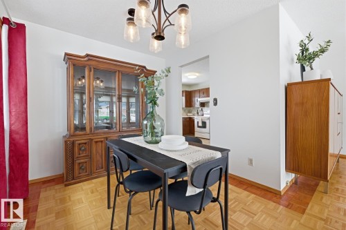 Dining area featuring parquet flooring, a contemporary ceiling light fixture, and an open doorway providing a view into the kitchen - 16108 100 Street, Edmonton, AB - Indoor Photo Showing Dining Room