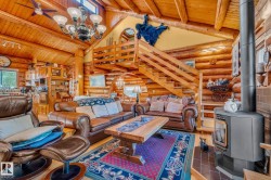 Spacious living room featuring log walls, a wood-burning stove, a wooden staircase, and a vaulted ceiling with exposed beams - 