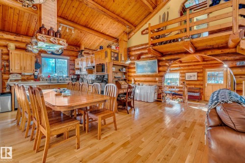 The property features an open living and dining area with hardwood floors and log walls - 60017 Range Road 42, Rural Barrhead County, AB - Indoor Photo Showing Dining Room