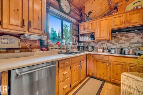 Kitchen featuring wood cabinetry, a stainless steel dishwasher, and a window with an outdoor view - 60017 Range Road 42, Rural Barrhead County, AB - Indoor Photo Showing Kitchen With Double Sink