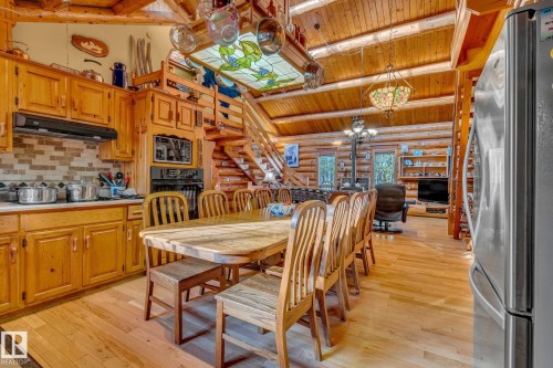 The main living area features exposed log beams, hardwood flooring, and a stone backsplash in the kitchen - 60017 Range Road 42, Rural Barrhead County, AB - Indoor Photo Showing Other Room