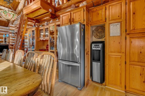 The property features natural wood walls and cabinetry, a stainless steel refrigerator, and a freestanding water dispenser - 60017 Range Road 42, Rural Barrhead County, AB - Indoor Photo Showing Dining Room