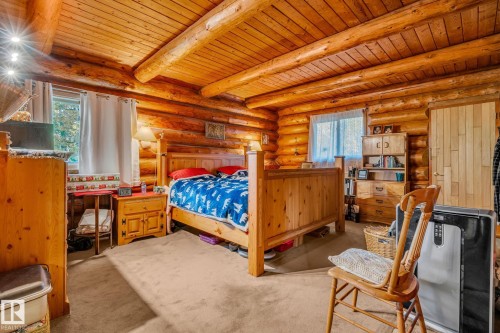 This space features exposed log walls and ceiling, creating a rustic aesthetic - 60017 Range Road 42, Rural Barrhead County, AB - Indoor Photo Showing Bedroom