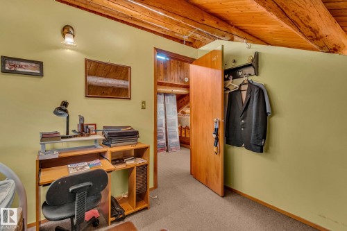 The property features a room with a sloped wooden ceiling, a desk area, and a doorway - 60017 Range Road 42, Rural Barrhead County, AB - Indoor