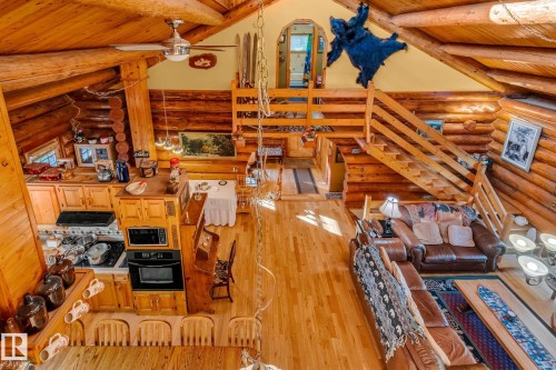 Spacious open-concept living area featuring exposed log beams, hardwood flooring, and a log staircase - 60017 Range Road 42, Rural Barrhead County, AB - Indoor Photo Showing Other Room