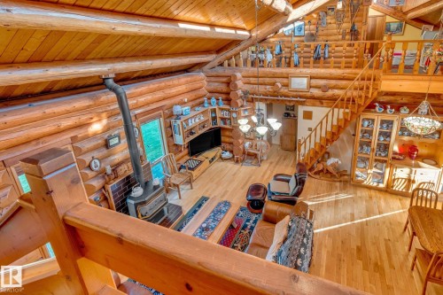 Expansive open-concept living space featuring natural wood log walls, high ceilings with exposed wood beams, and warm wood flooring - 60017 Range Road 42, Rural Barrhead County, AB - Indoor Photo Showing Other Room