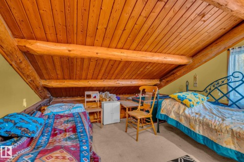 This space features prominent exposed log beams and a wood-paneled ceiling - 60017 Range Road 42, Rural Barrhead County, AB - Indoor Photo Showing Bedroom