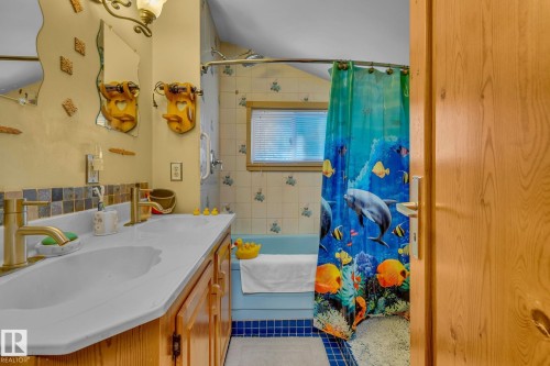 The bathroom features a double vanity with brass fixtures and a blue tiled backsplash - 60017 Range Road 42, Rural Barrhead County, AB - Indoor Photo Showing Bathroom