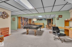 This spacious room features light green walls, a light-colored carpet, and a drop ceiling with integrated lighting - 