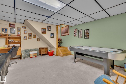 The property features a spacious room with light-colored carpeting, a drop ceiling, and light green accent walls - 60017 Range Road 42, Rural Barrhead County, AB - Indoor Photo Showing Other Room