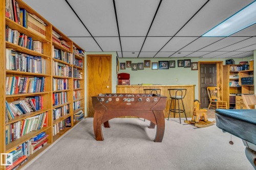 This versatile space features extensive built-in wooden shelving, a carpeted floor, and a drop ceiling - 60017 Range Road 42, Rural Barrhead County, AB - Indoor
